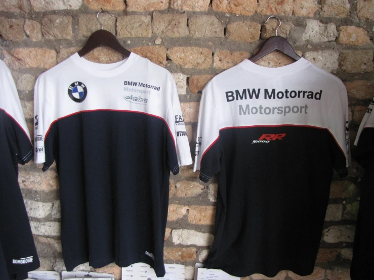 bmw motocross t shirts hang from a brick wall