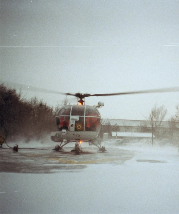 a small red and white helicopter on some snow