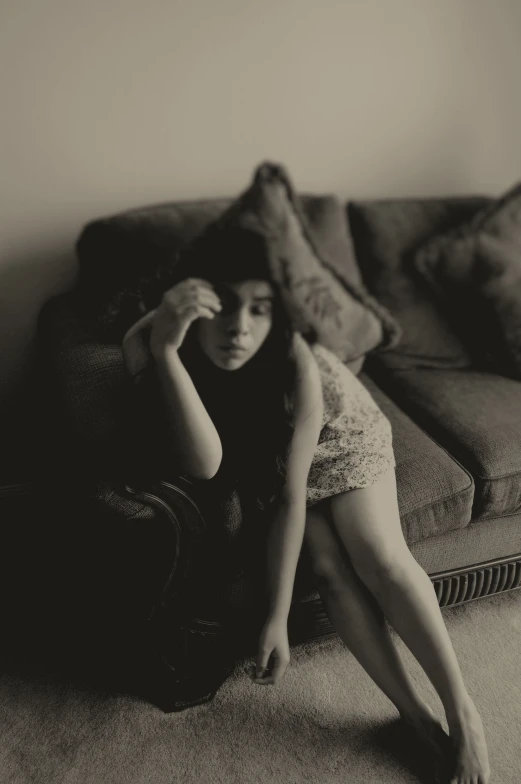 a girl sitting on a couch and holding her head while posing for a po