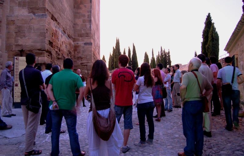 a crowd of people walking up a street on a sunny day