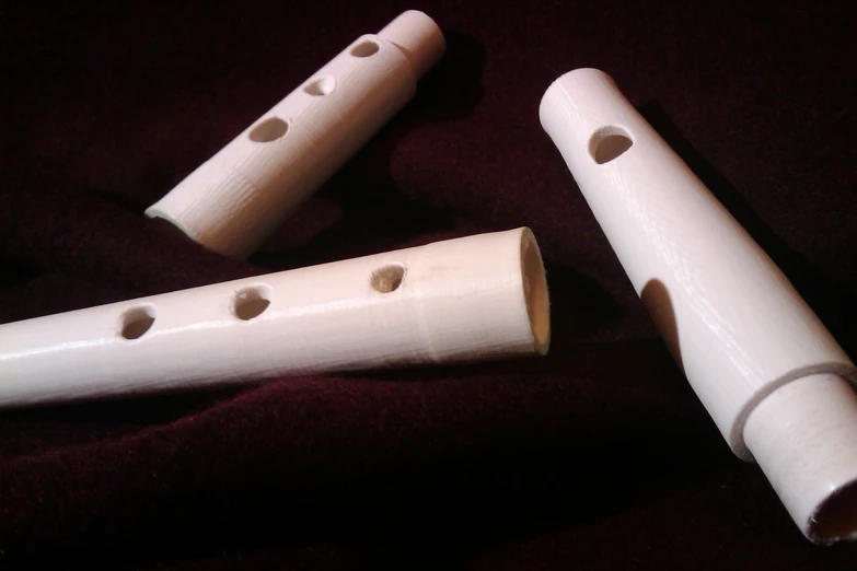 two flutes with holes sit on top of a purple cloth