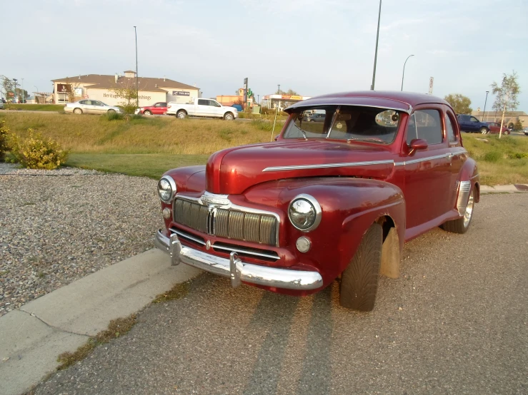 a red old pick up parked in the middle of a street