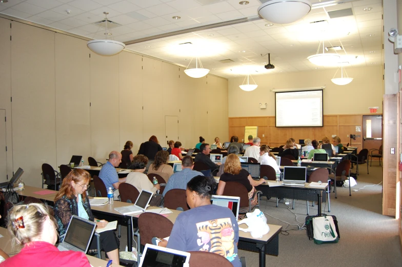 an auditorium filled with people sitting in chairs while using laptops