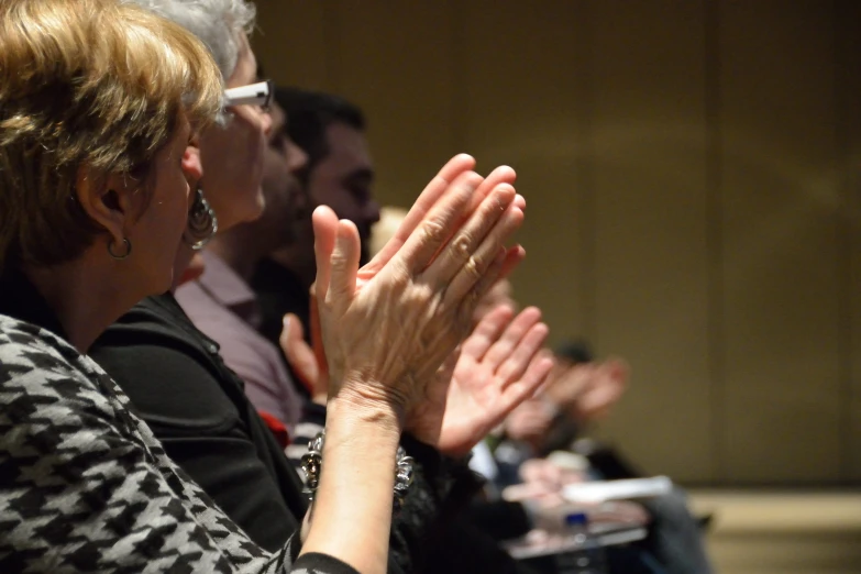 people standing and clapping their hands at a meeting