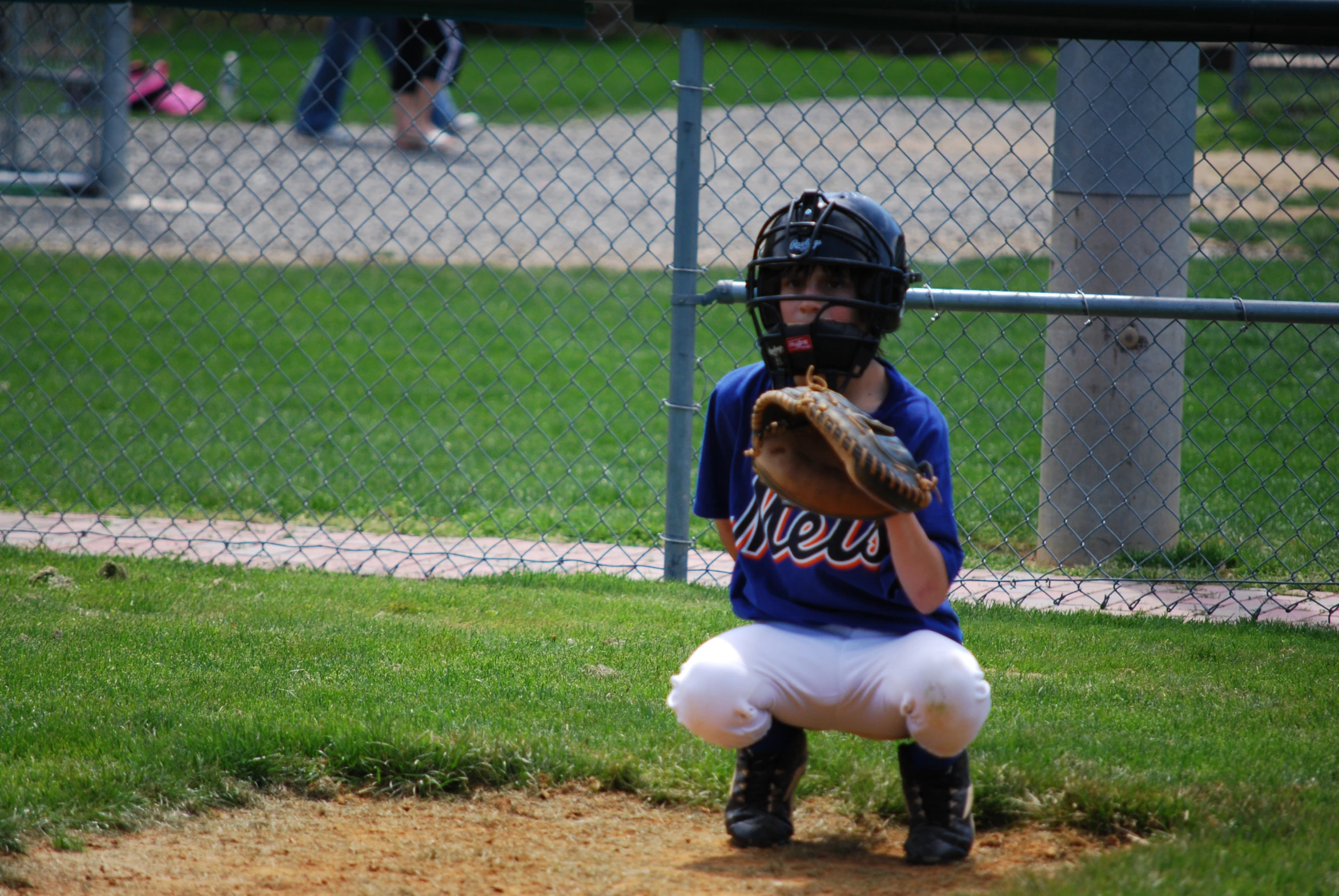 a  squatting while holding a baseball mitt