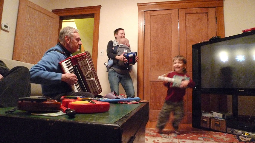 a man and little boy play together with a large accordion