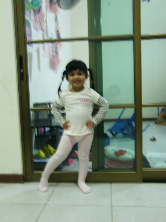 a small girl wearing a white t shirt and pink tights