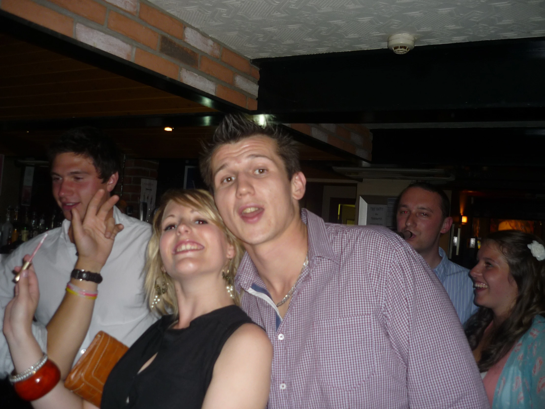 three adults in a crowded bar posing for the camera