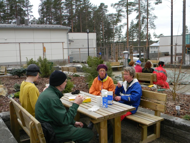 some people sitting at picnic tables having lunch together