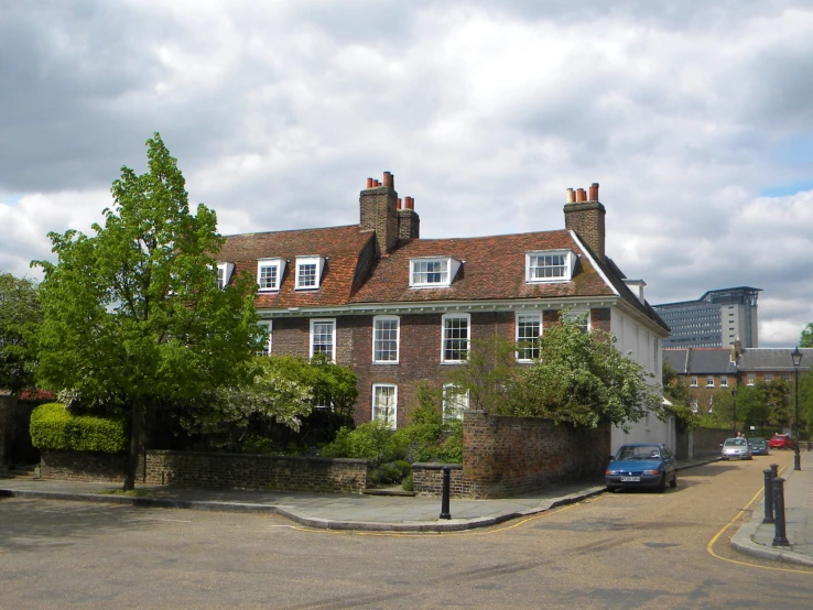 an old brick home surrounded by trees and a street