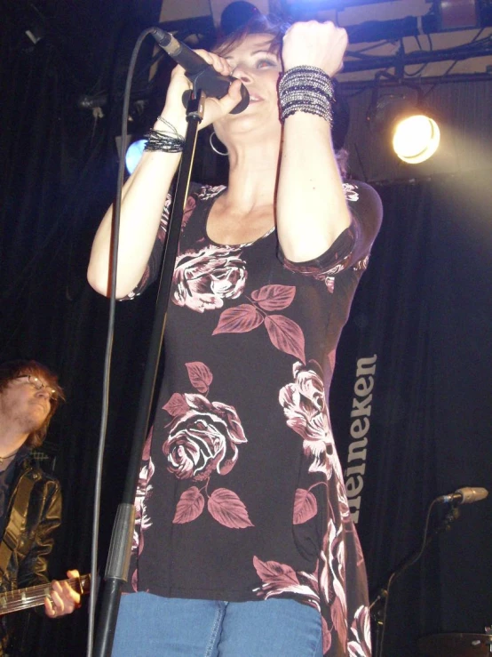 woman singing on stage during a performance with one hand raised