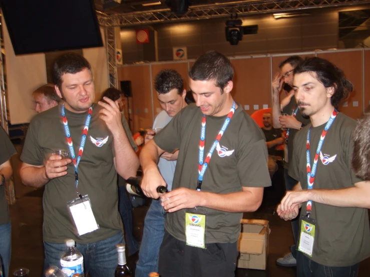 people in green shirts are standing and holding wine bottles