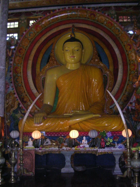 the buddha statue sits in front of a large painting