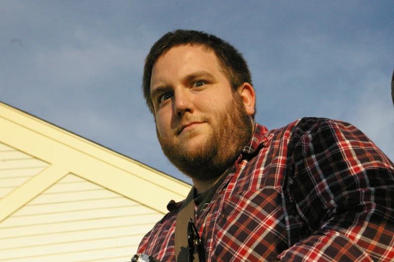 a man posing for the camera with a barn behind him