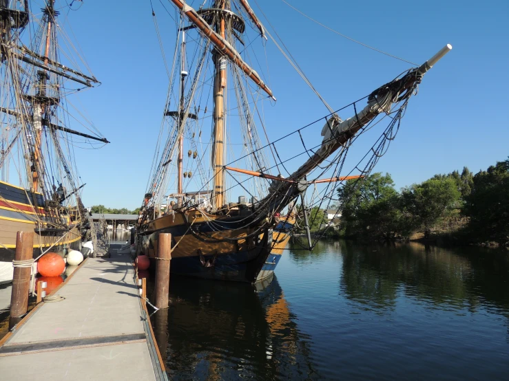 a tall ship sitting next to a wooden dock