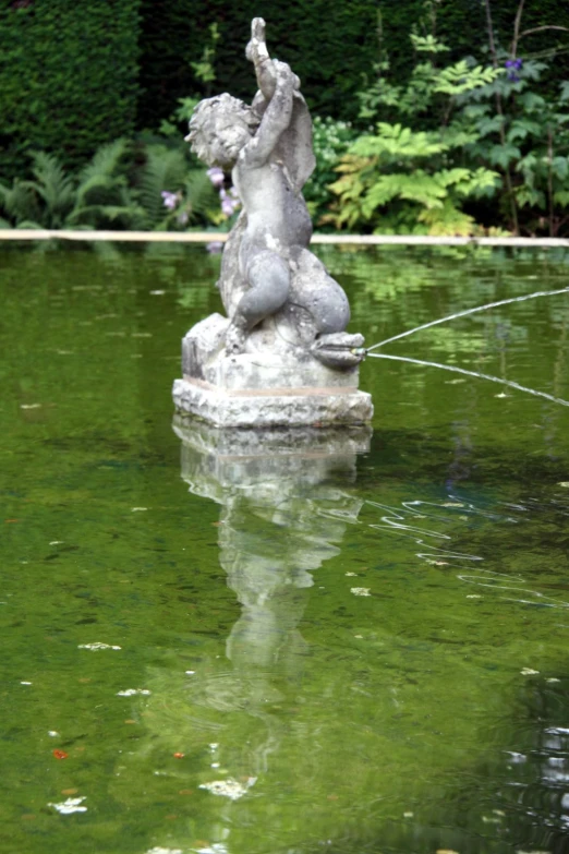 a statue in the middle of a pond with a person on it