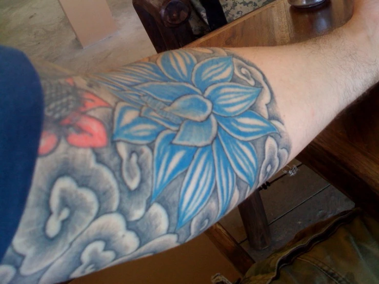 a tattooed arm with a blue flower and black and white design