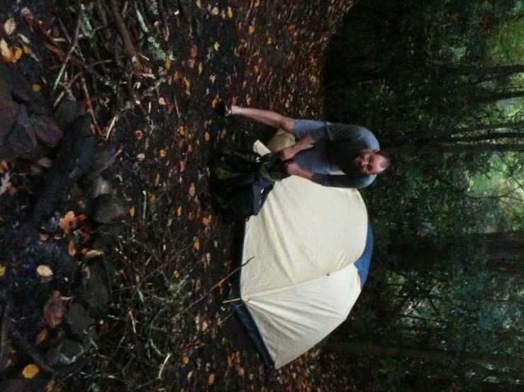 a man stands next to a tent and holds the back of his backpack