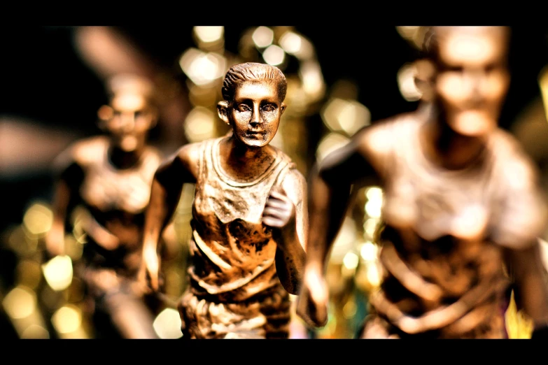 two little statues of people running behind one another