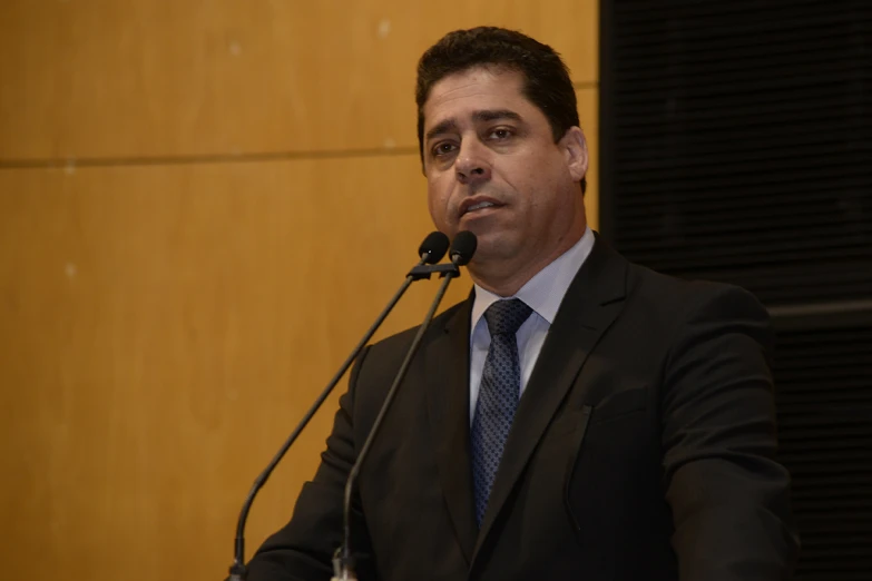 a man standing behind a microphone in front of a wall