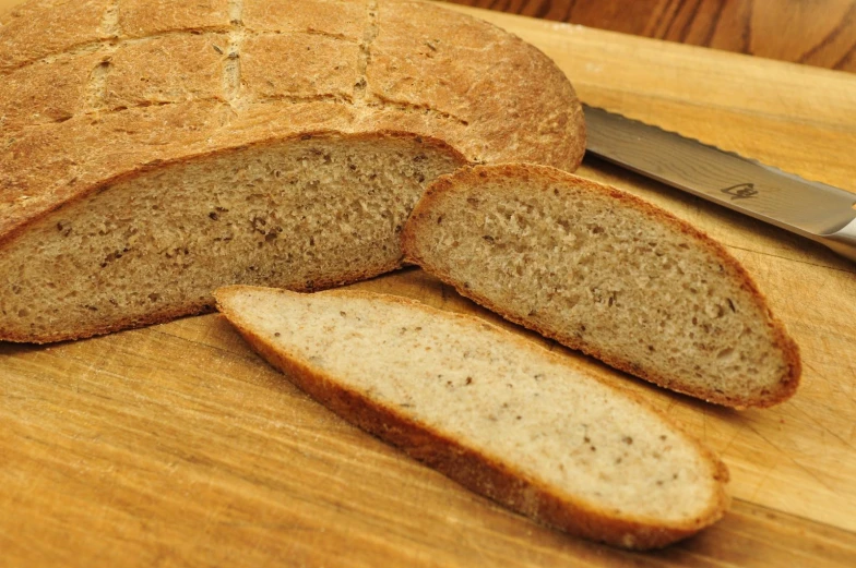 a piece of bread next to a knife on a  board