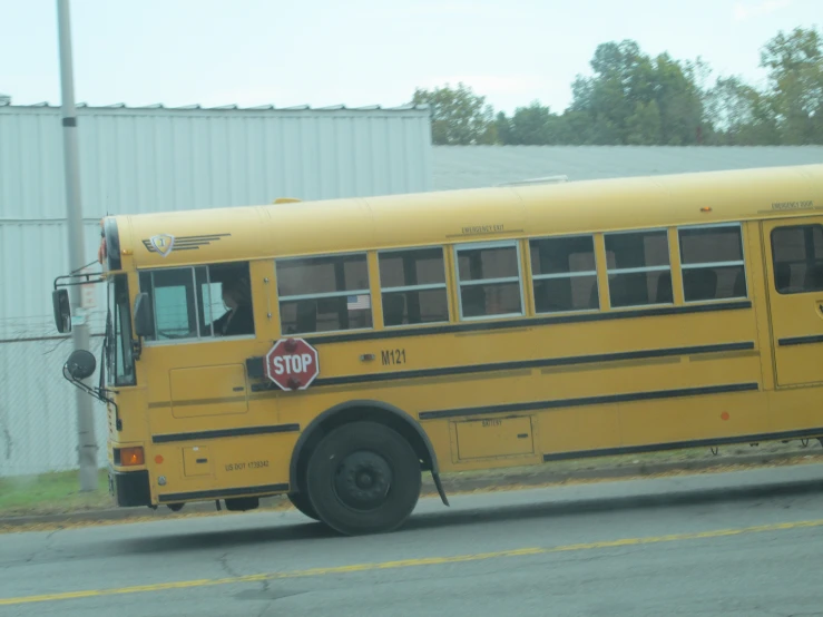 a yellow bus on street with trees in background