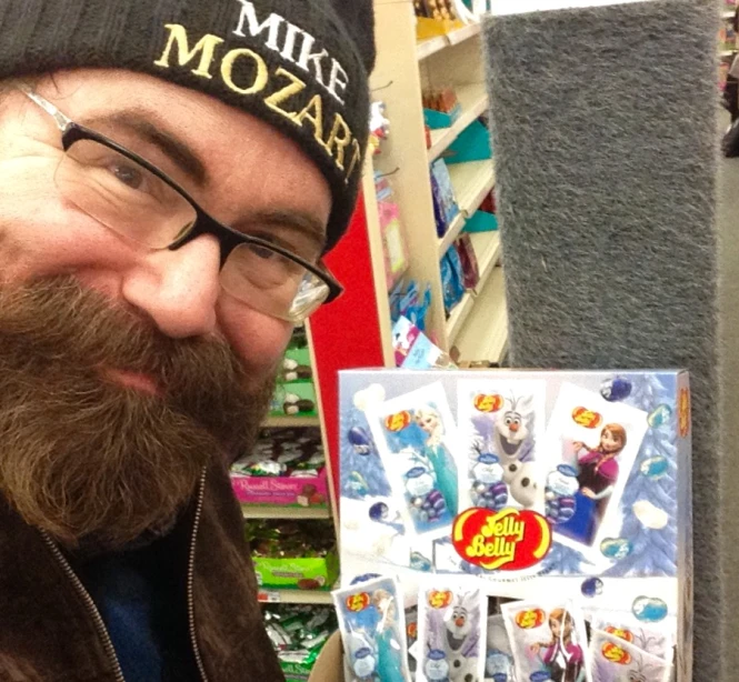 a man with glasses and a mustache on his head holding a book of disney minis