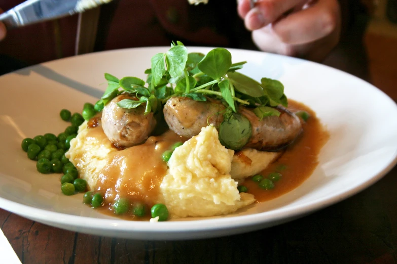 the dinner plate contains peas, mashed potatoes and meatballs