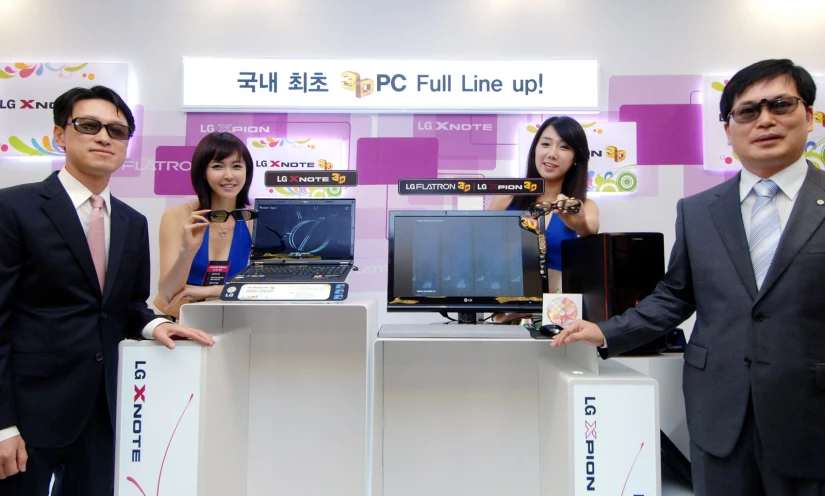 three asian people pose in front of the electronic computers