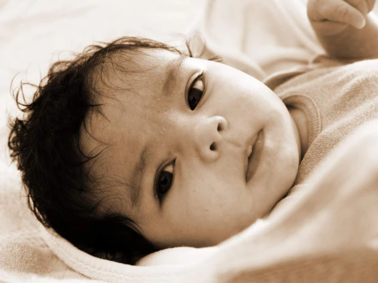 a baby is laying on a blanket and smiling