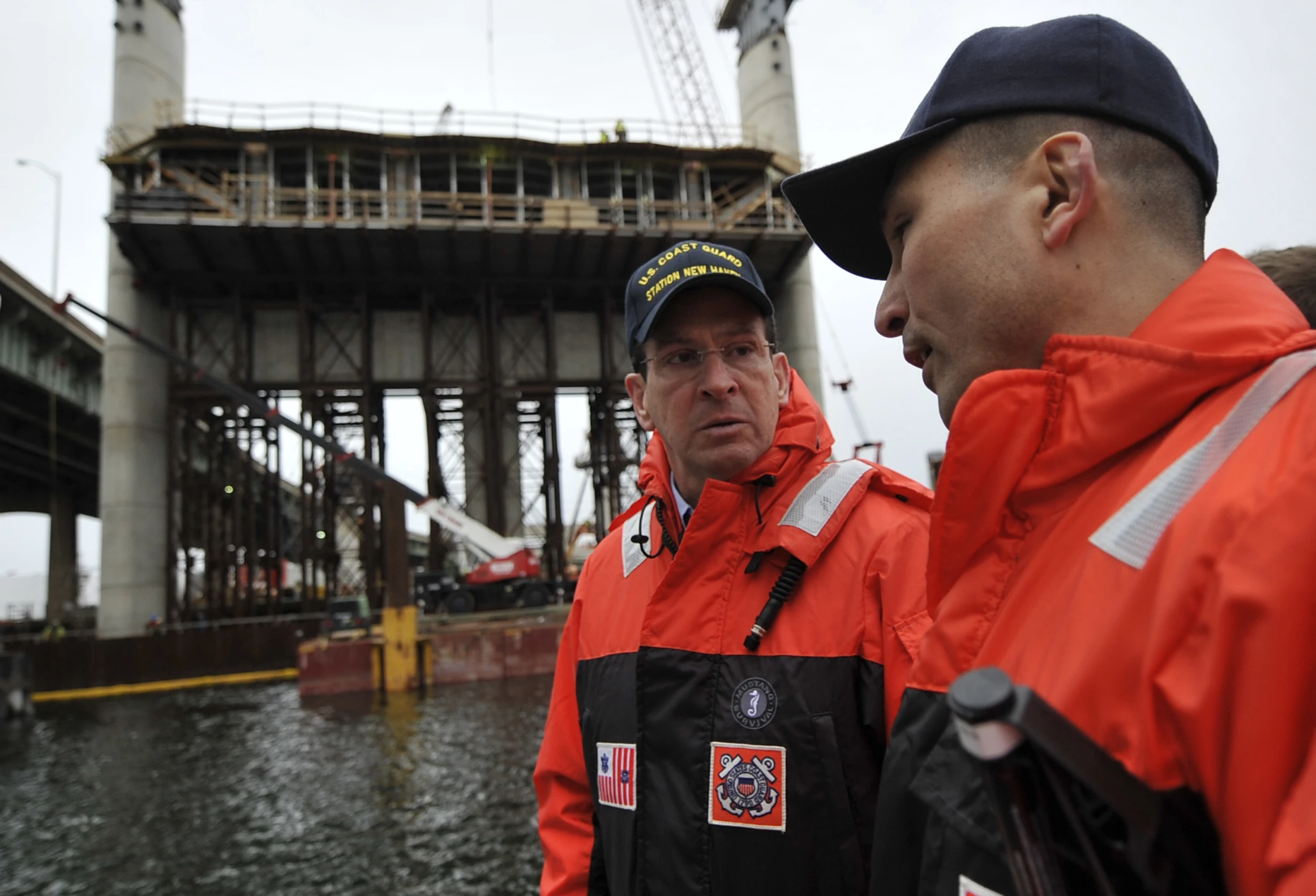 two workers wearing orange jackets standing outside