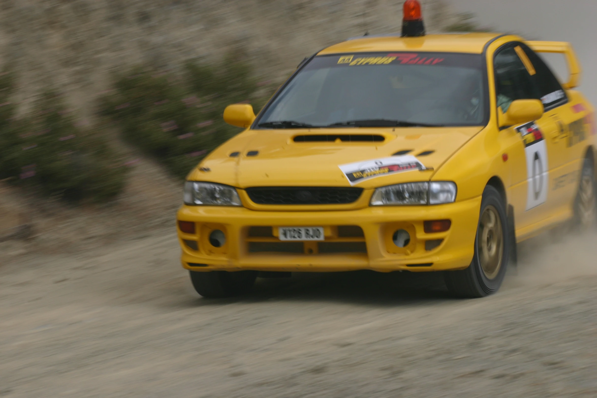 a yellow toyota car making its way through the dirt