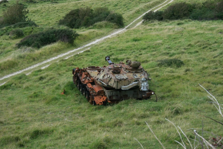 an abandoned military tank sits in a grassy field