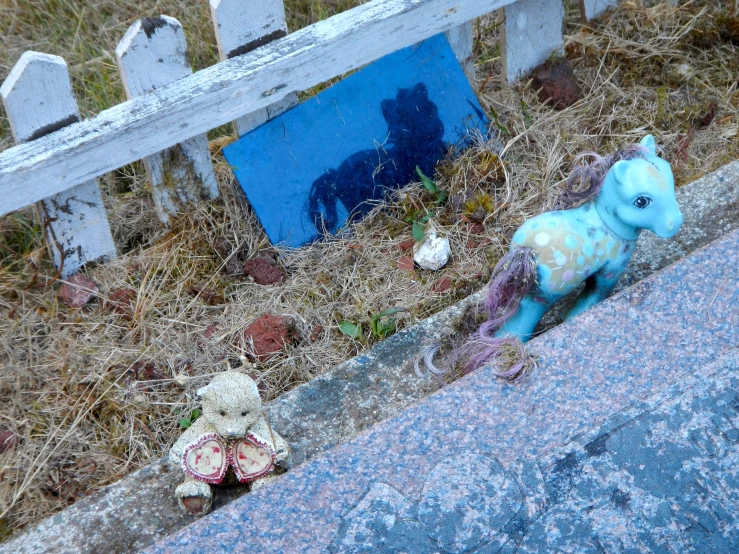 some teddy bears are on the ground near a picket fence