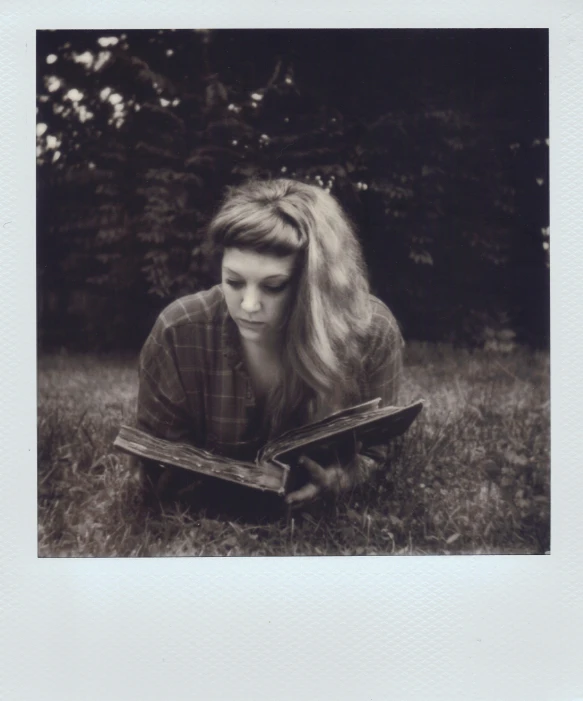 there is a woman reading a book on the grass