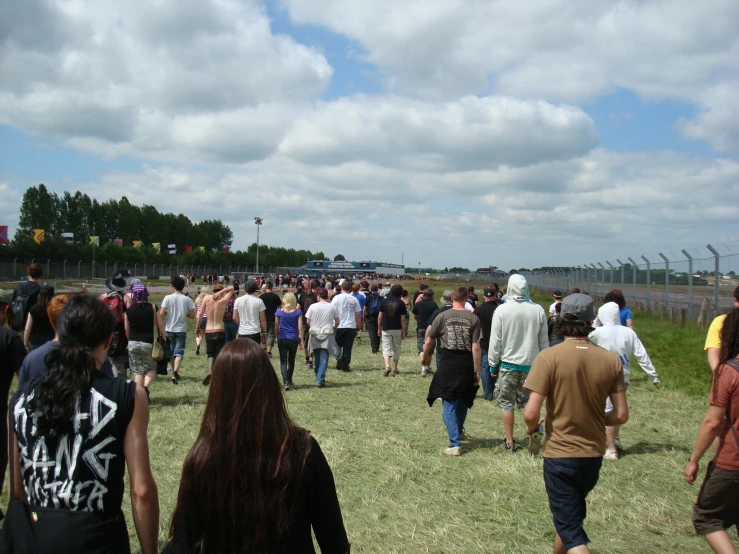 a crowd of people walking in the grass with one man on a cellphone