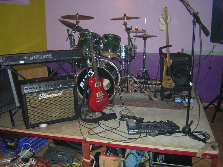 guitars and amps are stacked on top of a shelf