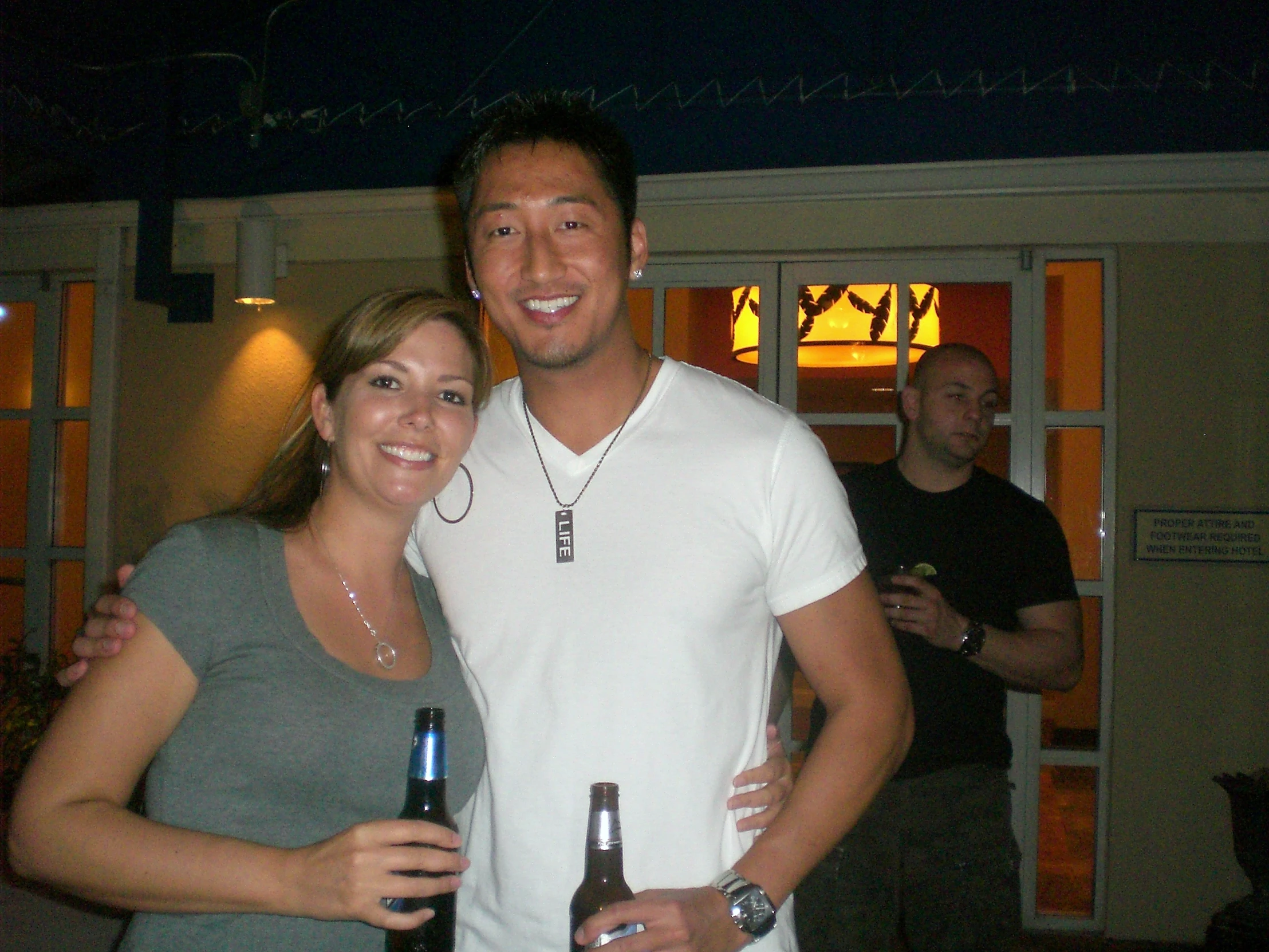 two people standing together with one holding a beer