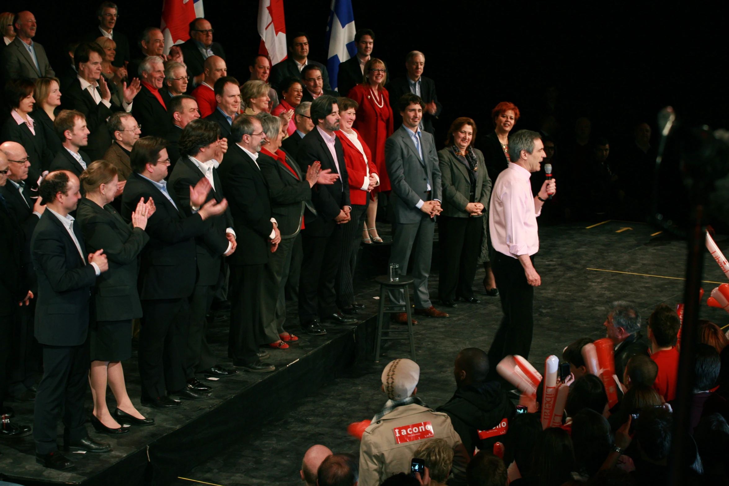 an image of a woman talking into microphone in front of people