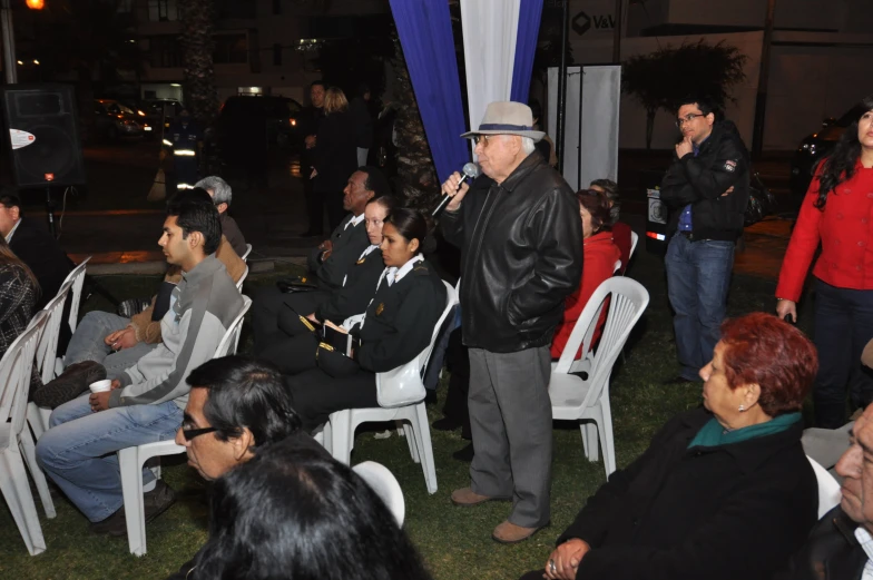 an audience of people sitting on lawn chairs watching two speakers