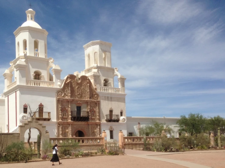 a girl walking by an ornate building with clock on it