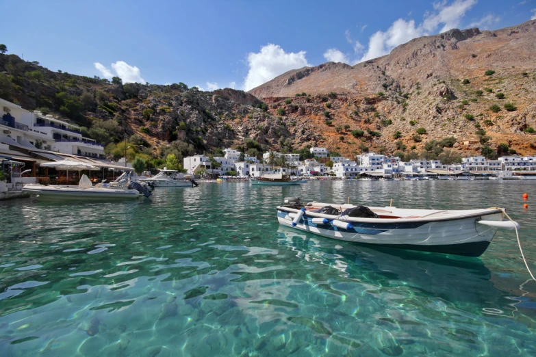 a couple of boats are in the water by a hill