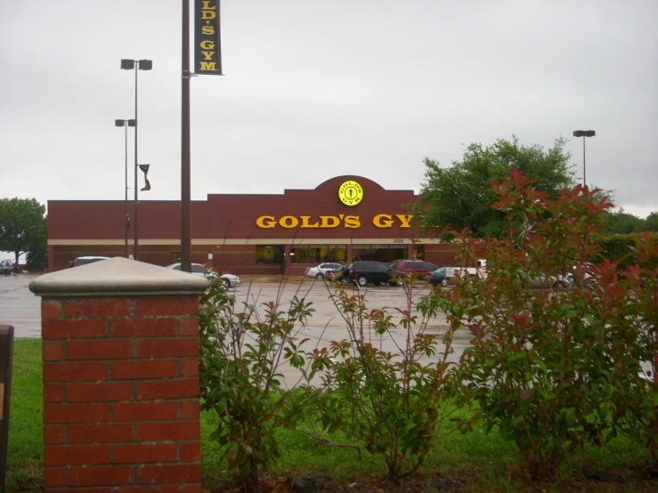 the entrance to golds gym with bushes growing around