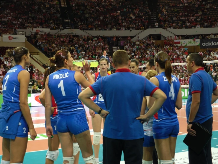 a bunch of volleyball players huddled at a match