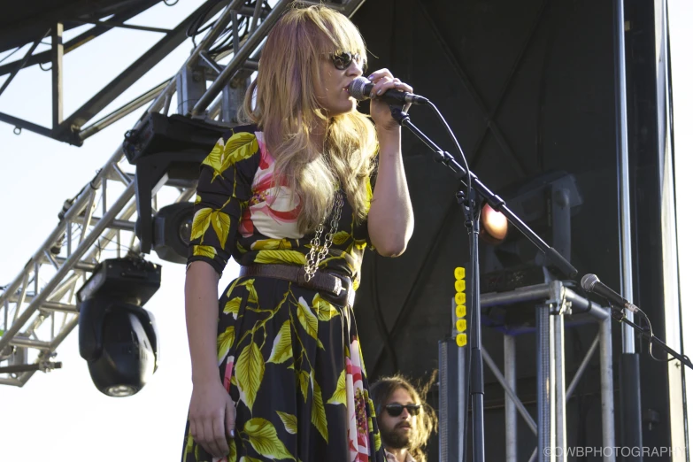 a woman in sunglasses holding up a microphone