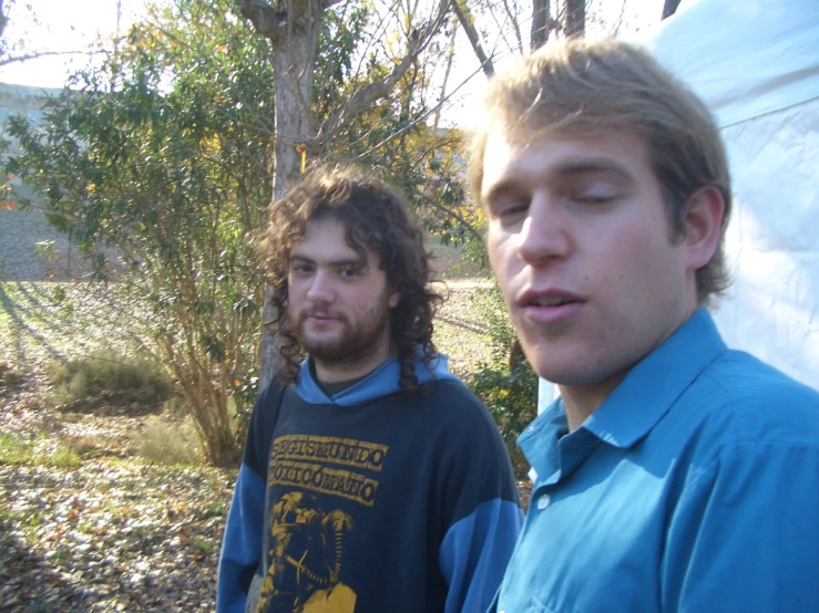 two men standing near one another in front of trees