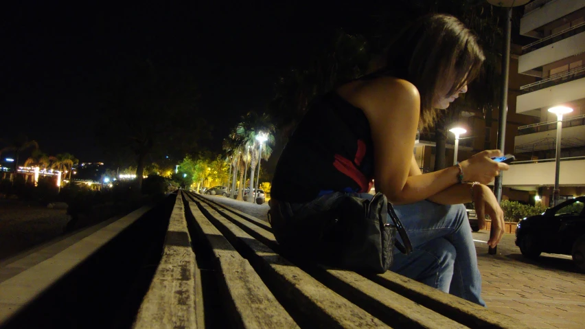 a woman standing in front of a bench while using her cellphone