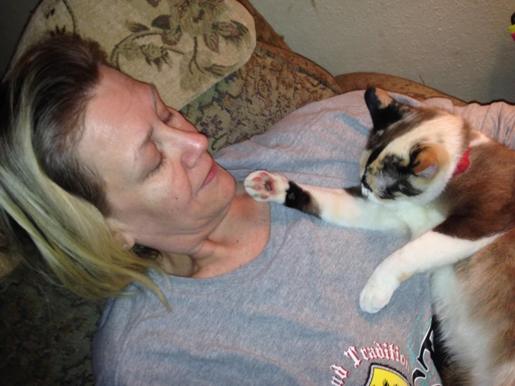 a woman holding a cat with two paws on it's chest