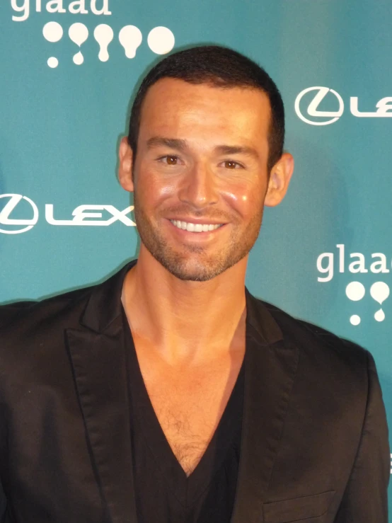 a smiling man in a black suit jacket posing for a po