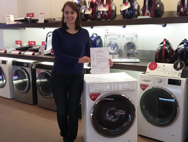 the woman is holding up a letter while standing next to washers